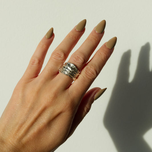Hand wearing the Canyon silver ring on a plain background.