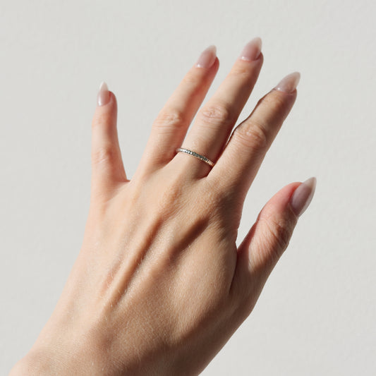 Hand wearing the Echo textured silver ring on a plain background.