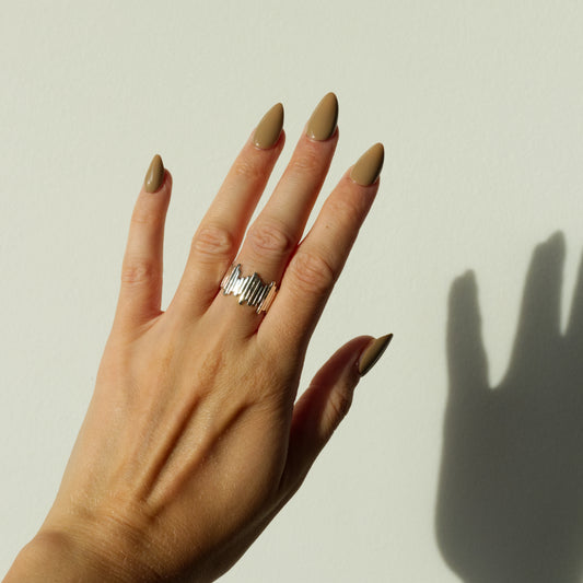 Hand wearing the Guidance silver ring on a plain background.