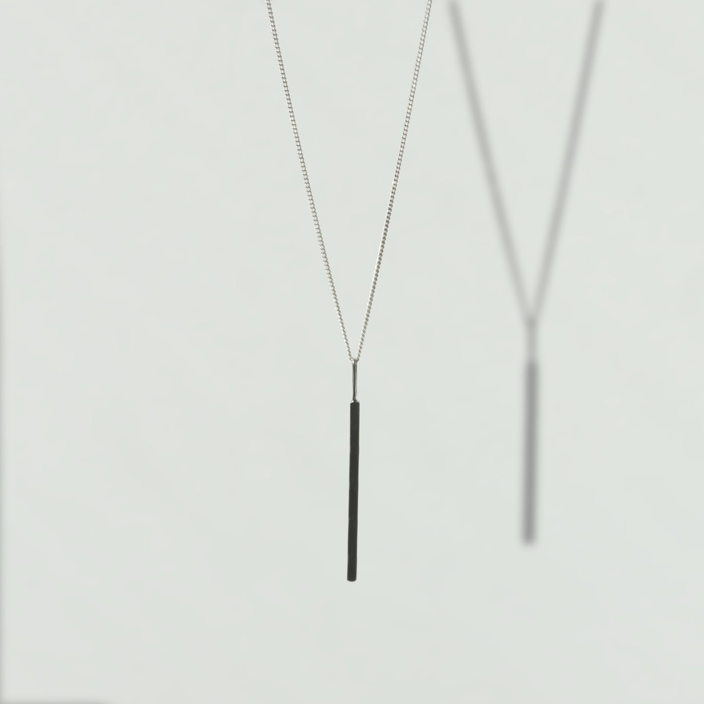 Front view of the Alignment silver bar pendant on a curb chain, pictured on a light plain background.