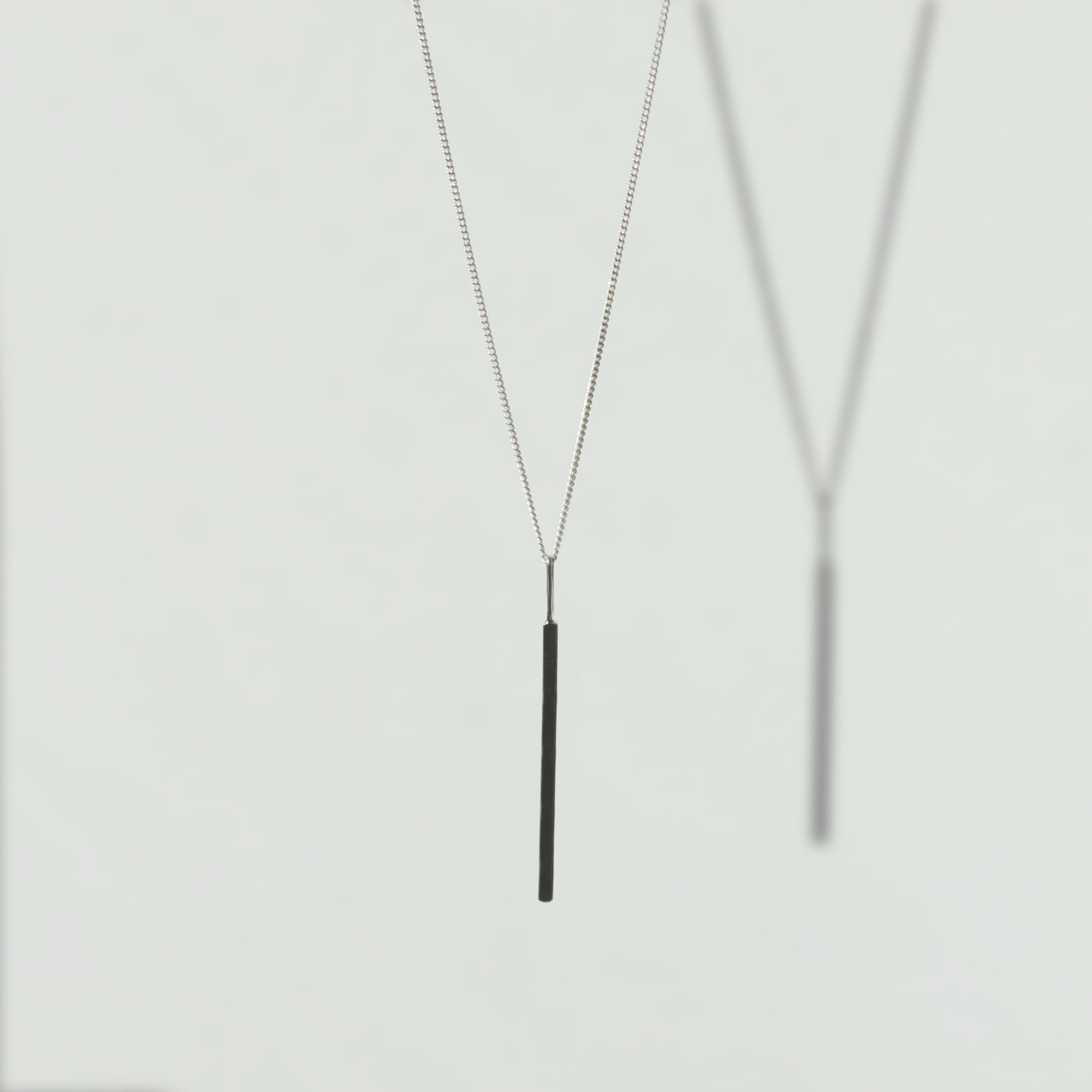 Front view of the Alignment silver bar pendant on a curb chain, pictured on a light plain background.