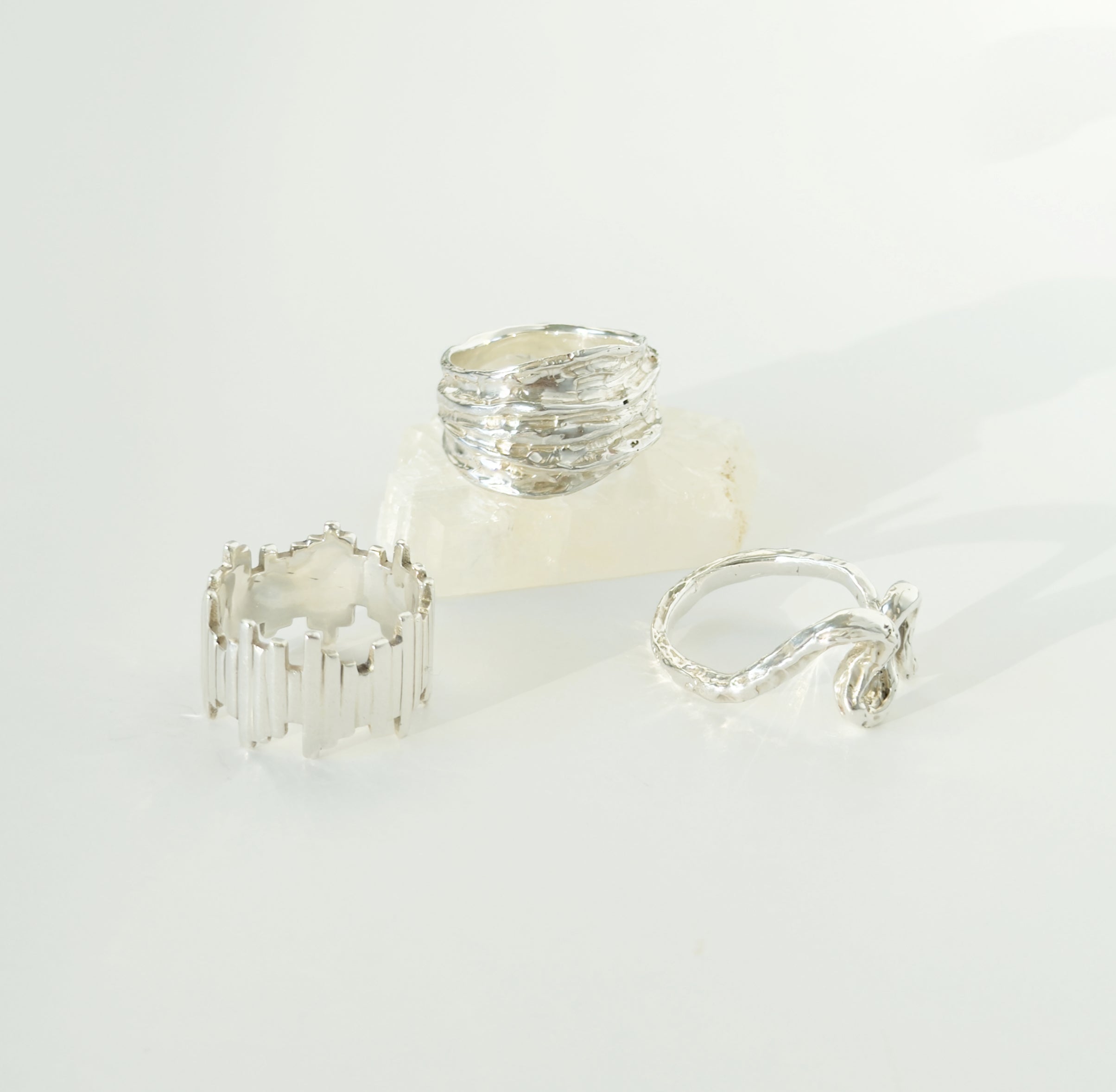 Three textured silver rings with different designs on a light background.