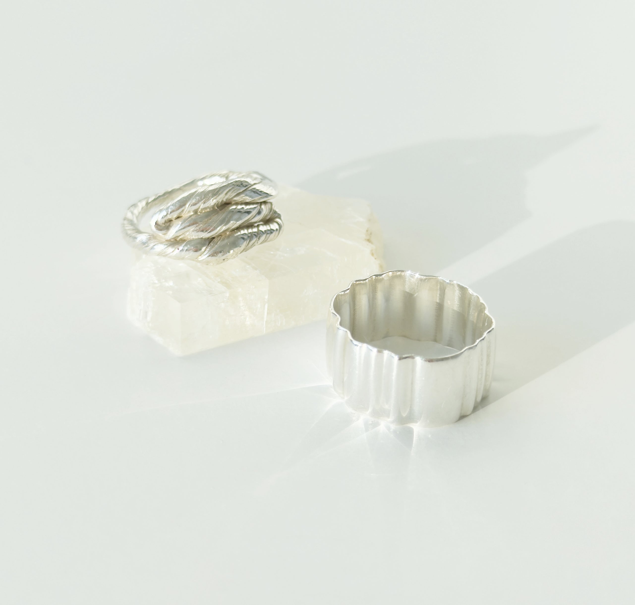 Two textured silver rings on a light plain background.