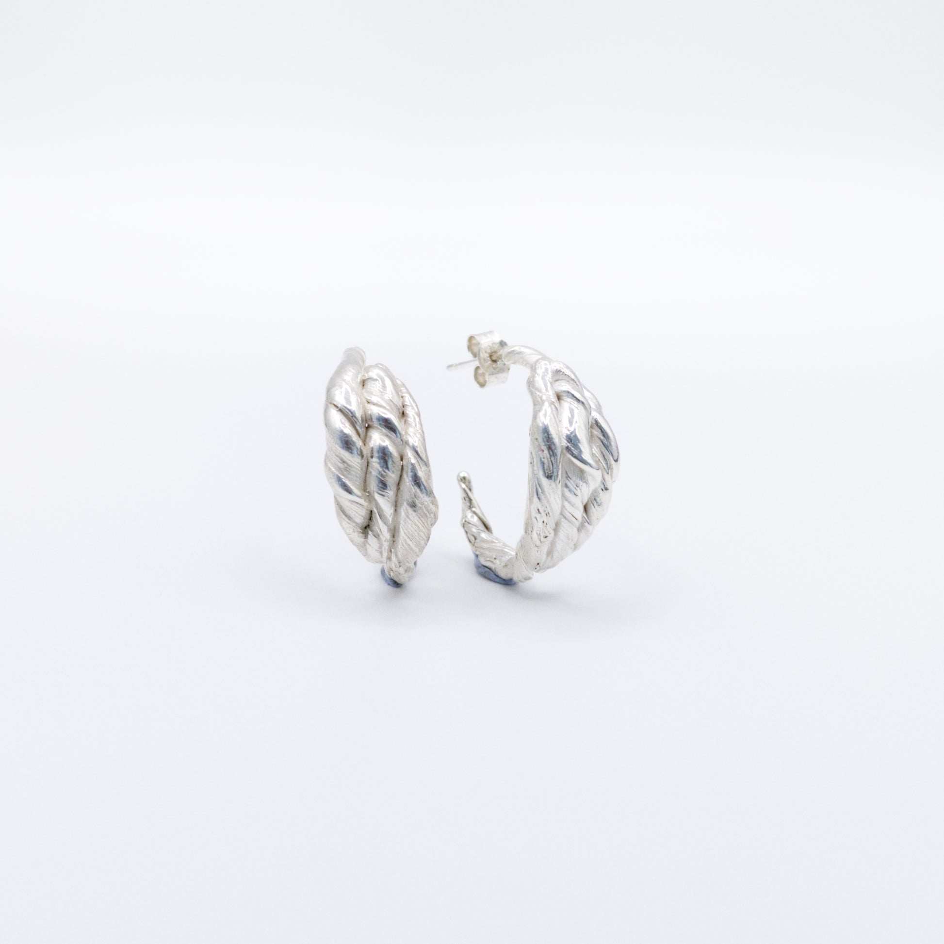 Front view of a pair of Anchor silver hoop earrings, pictured on a light plain background.