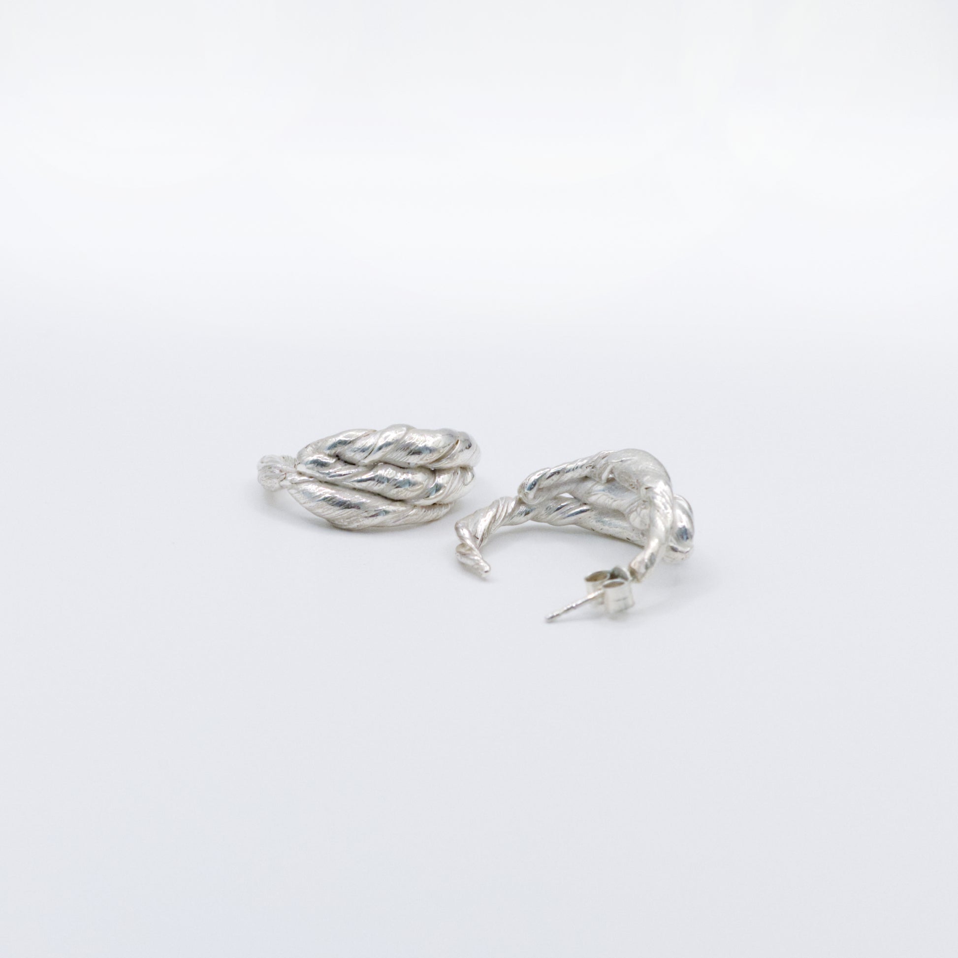 A pair of Anchor silver hoop earrings, front and back views, pictured on a light plain background.