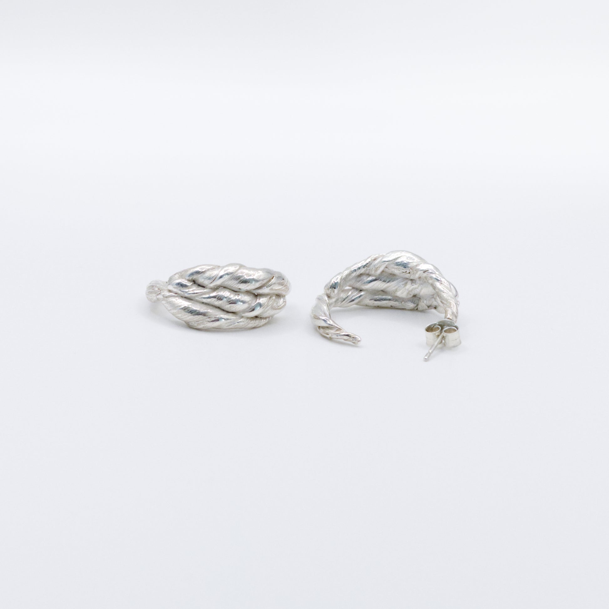 A pair of Anchor silver hoop earrings, front and back views, pictured on a light plain background.