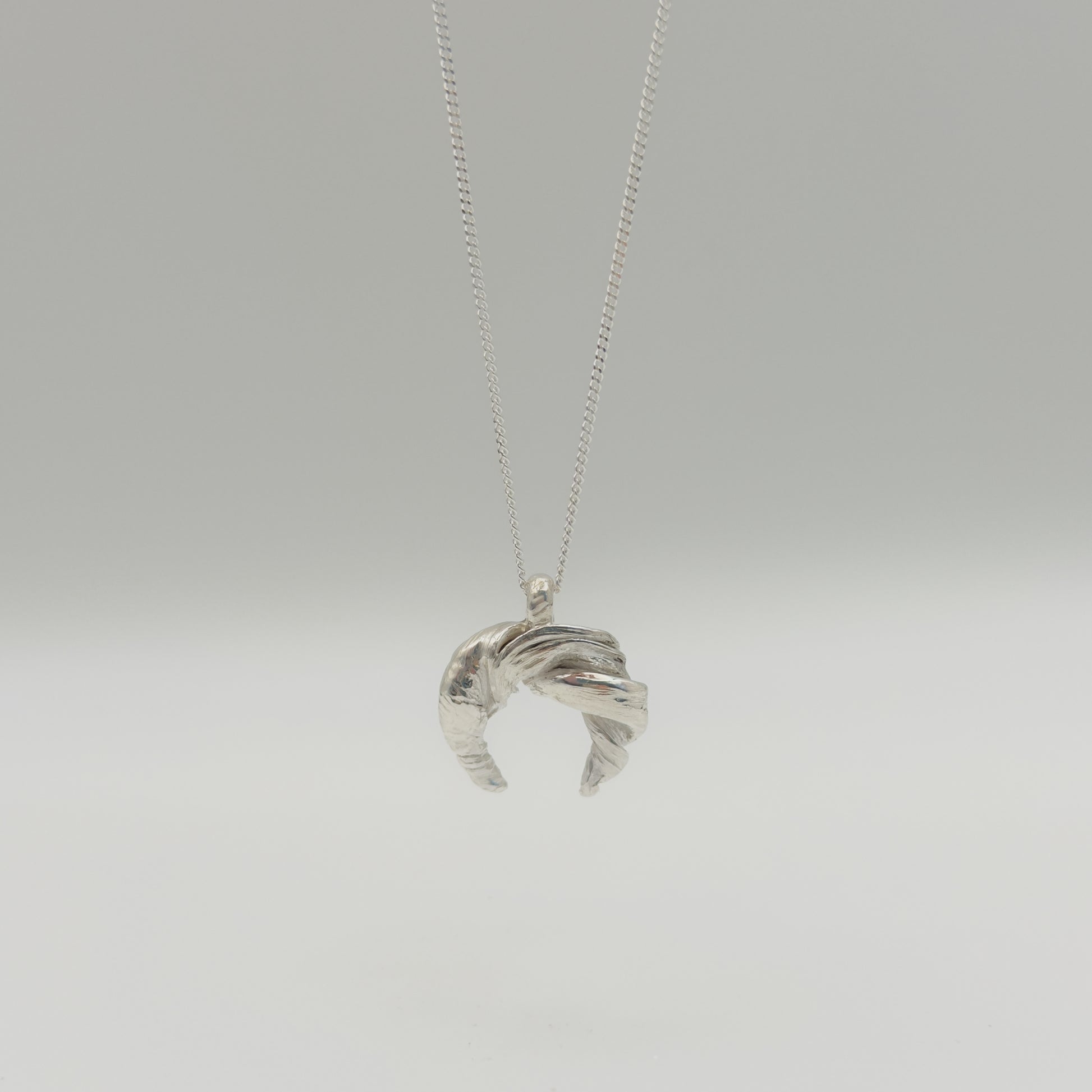 Front view of the Arc textured silver pendant on a chain, pictured on a light plain background.