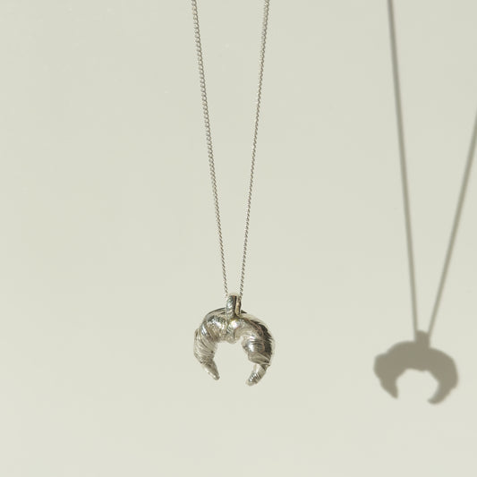 Angled front view of the Arc textured silver pendant on a chain, pictured on a light plain background.