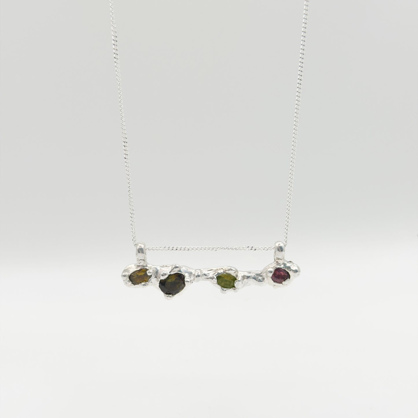 Front view of the Atoll Editions No1 silver necklace, featuring a textured bar pendant with multicolored tourmalines. Shown on a plain light background.