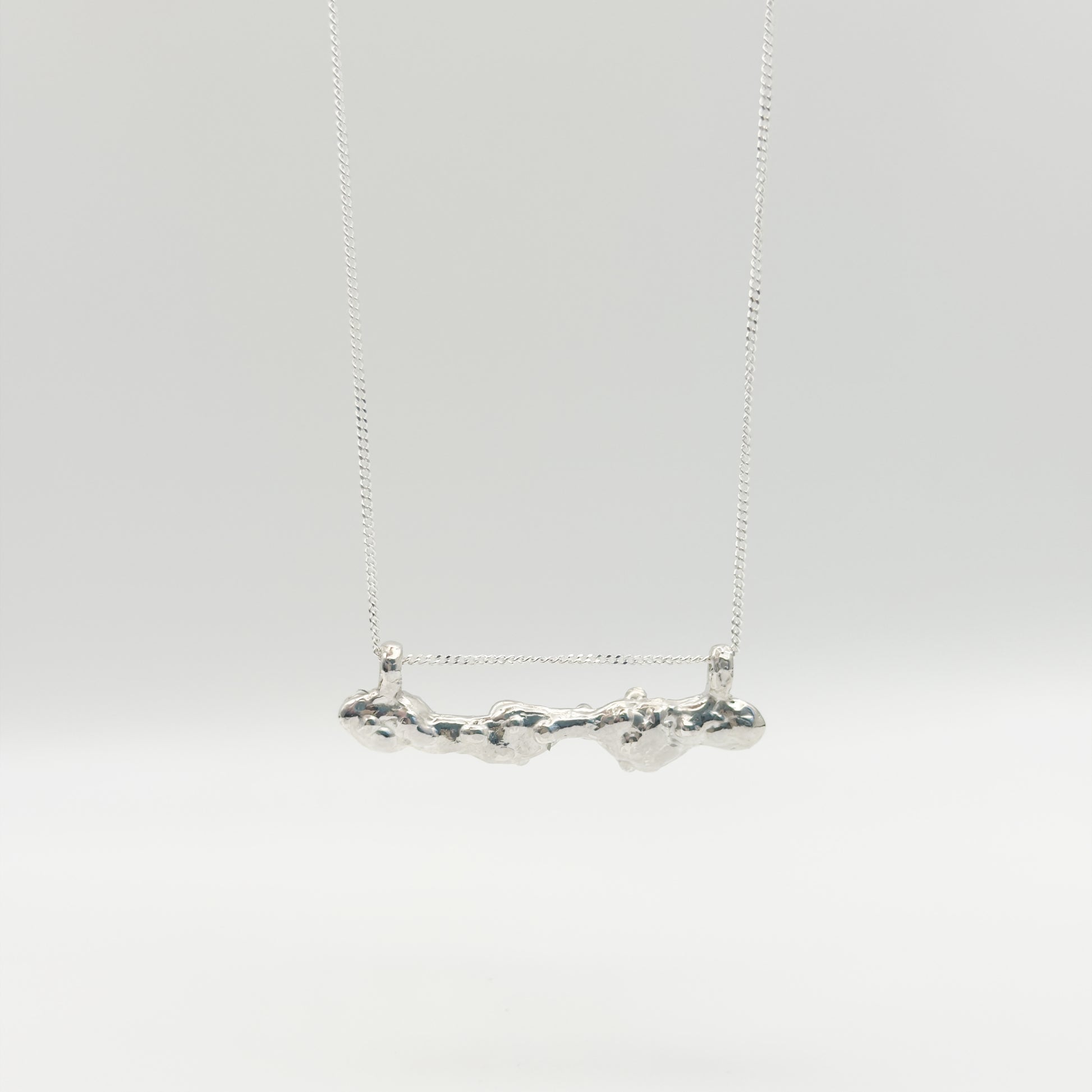 Back view of the Atoll Editions No1 silver necklace, featuring a textured bar pendant. Shown on a plain light background.