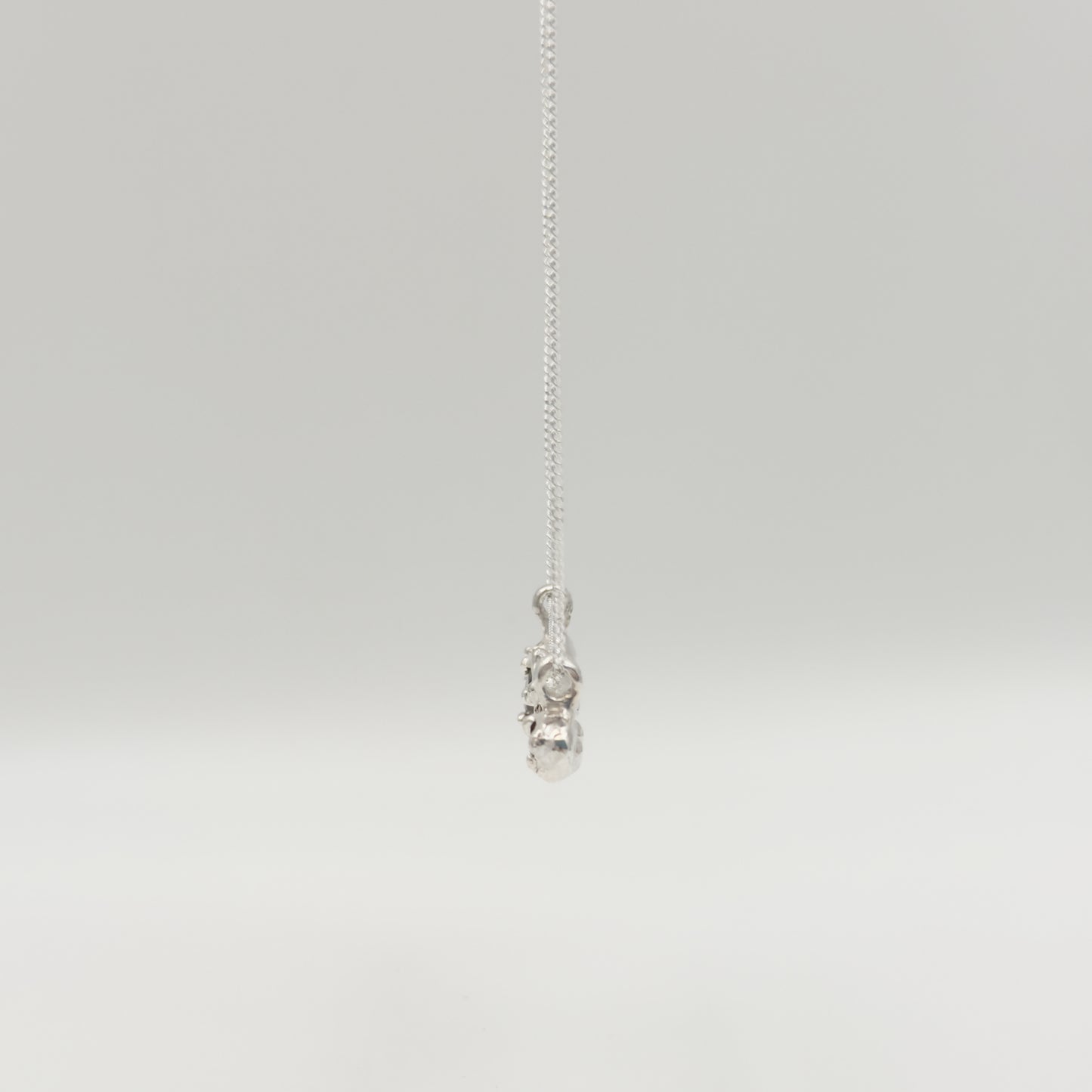 Side view of the Atoll Editions No1 silver necklace, featuring a textured bar pendant. Shown on a plain light background.