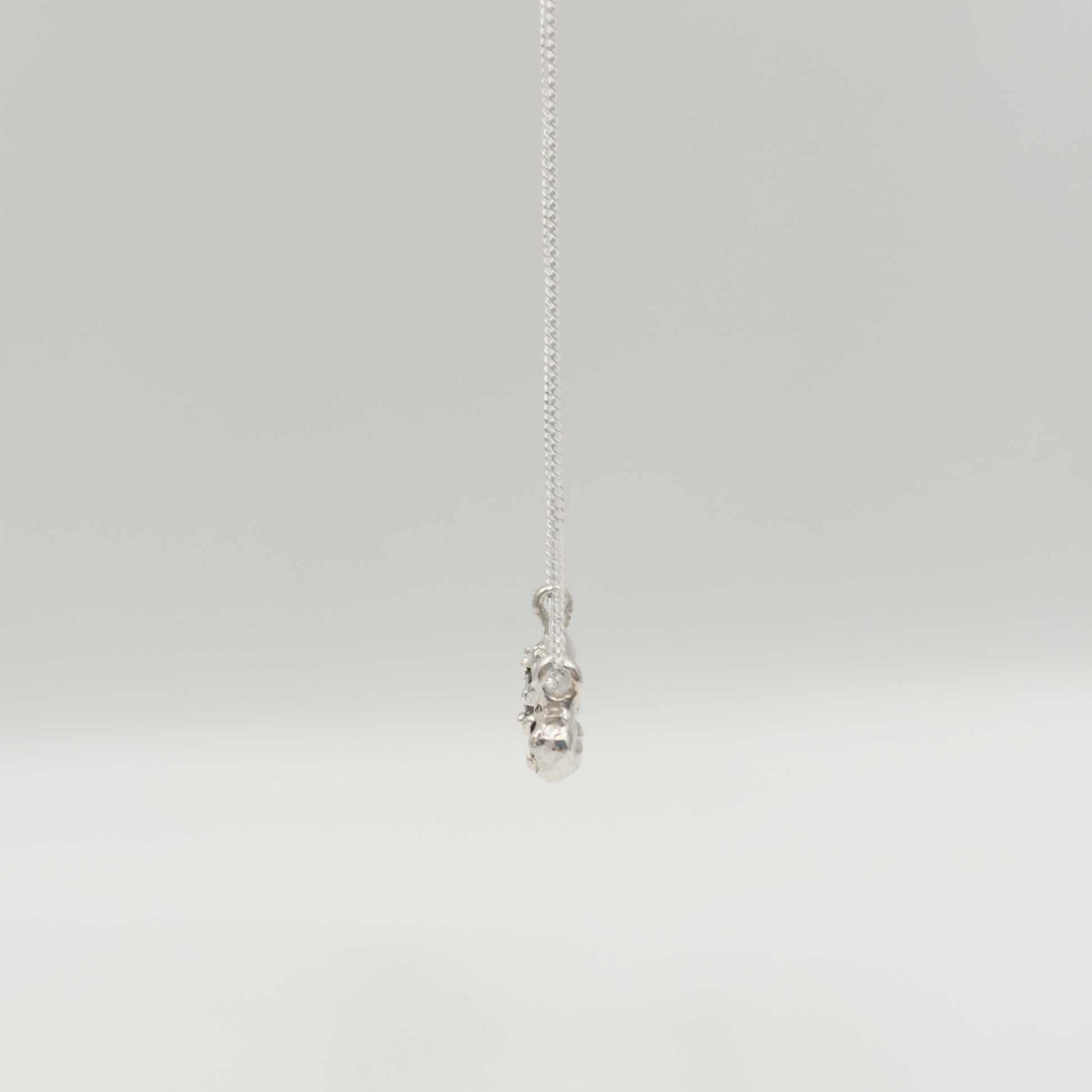 Side view of the Atoll Editions No1 silver necklace, featuring a textured bar pendant. Shown on a plain light background.