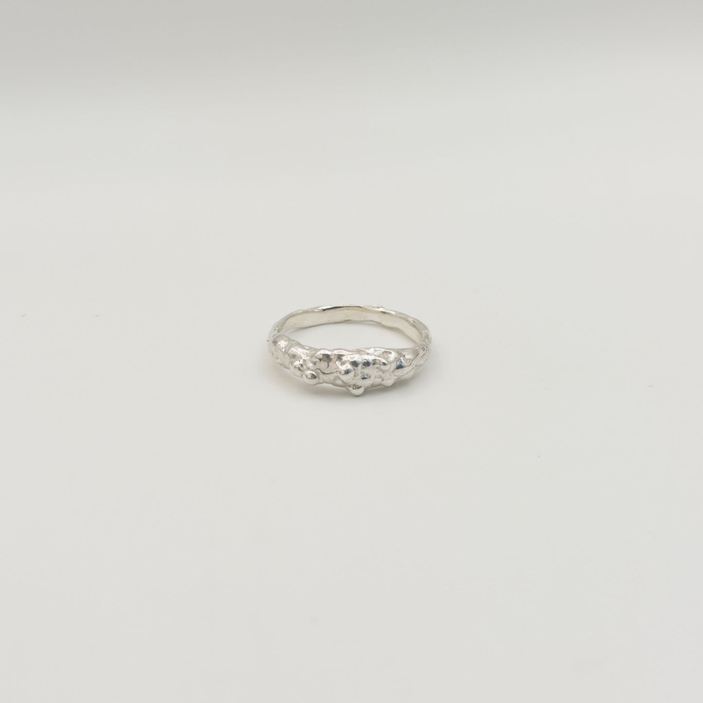 Front view of the Atoll textured silver ring, pictured on a light plain background.