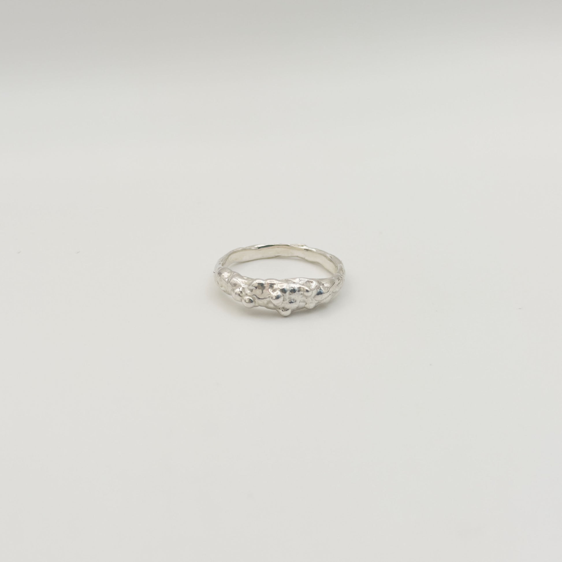 Front view of the Atoll textured silver ring, pictured on a light plain background.
