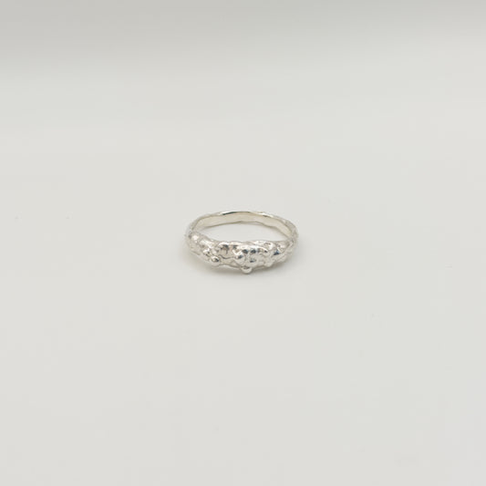 Front view of the Atoll textured silver ring, pictured on a light plain background.