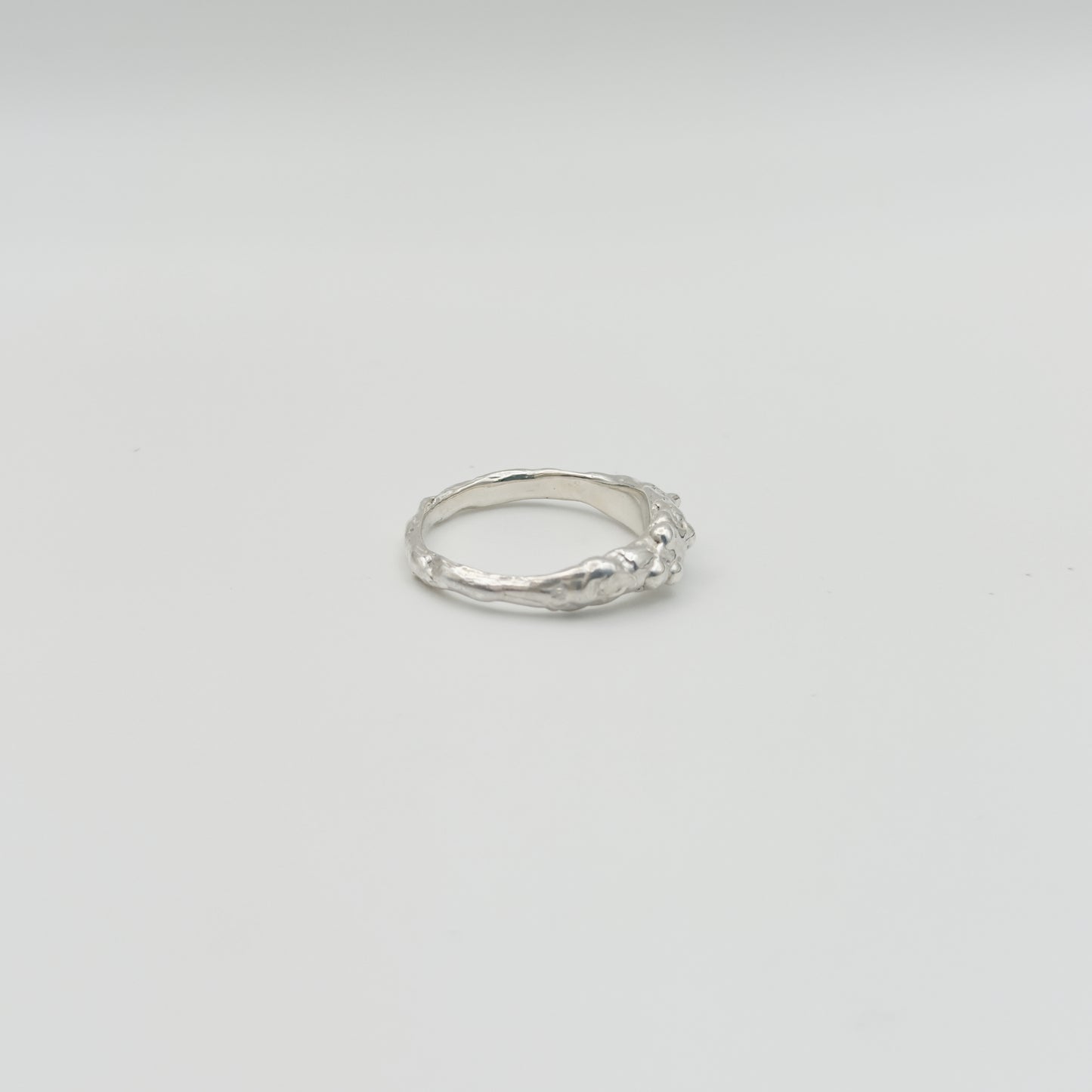 Side view of the Atoll textured silver ring, pictured on a light plain background.