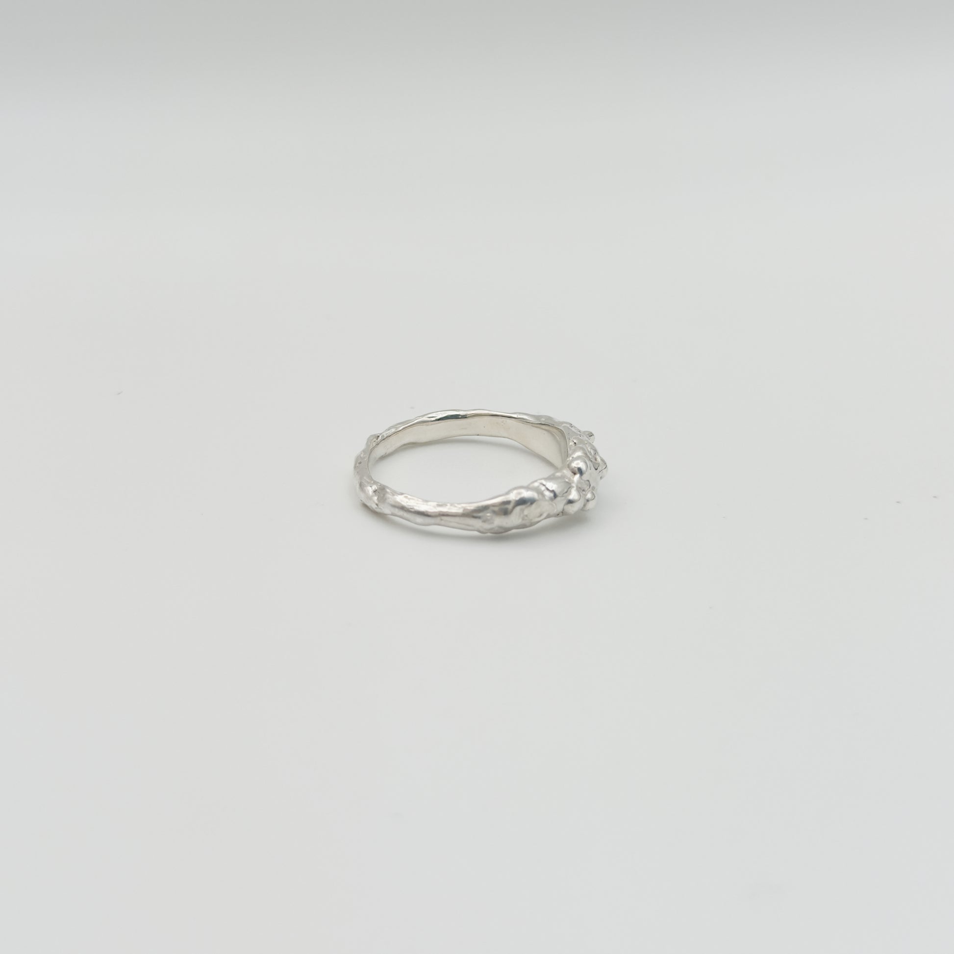 Side view of the Atoll textured silver ring, pictured on a light plain background.