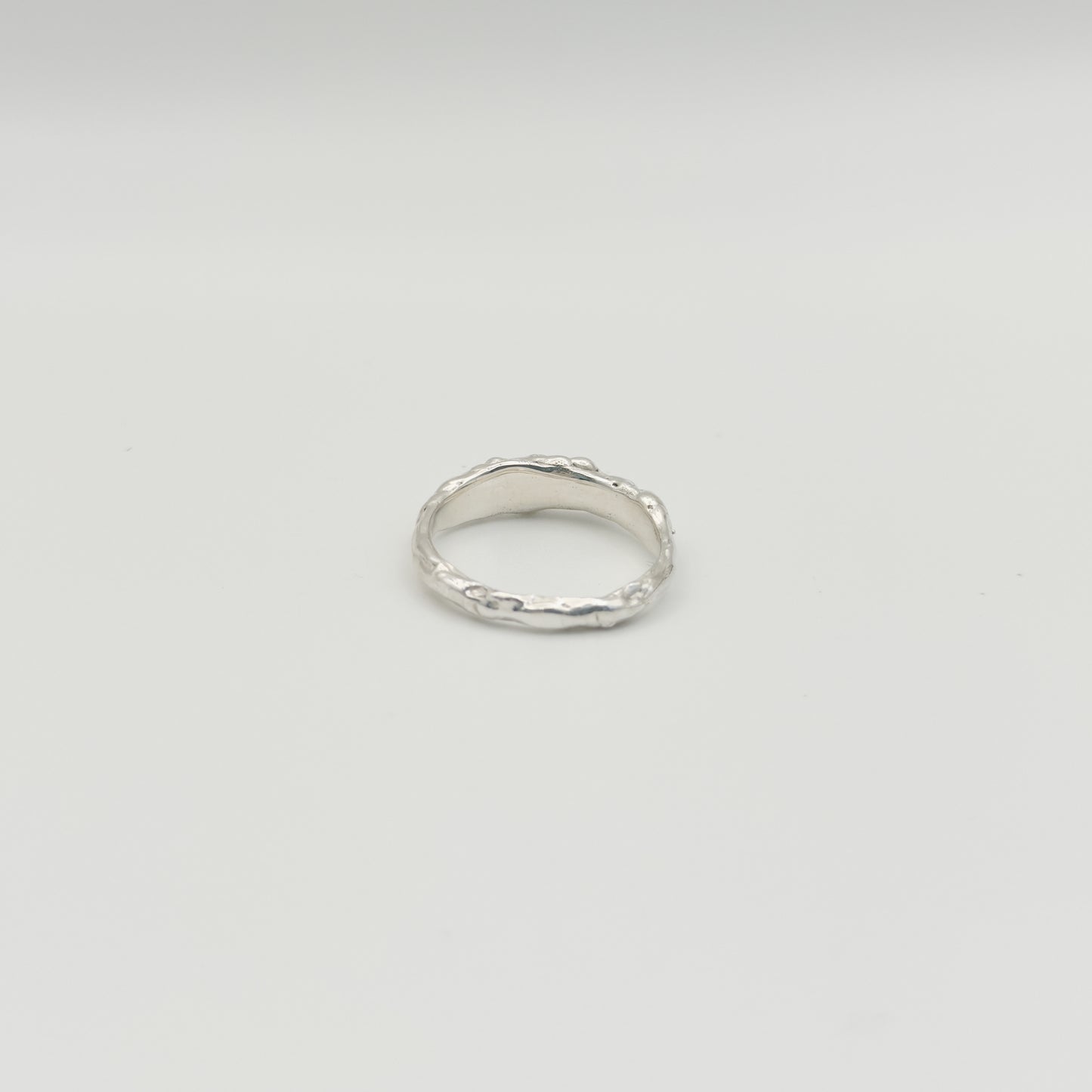 Back view of the Atoll textured silver ring, pictured on a light plain background.