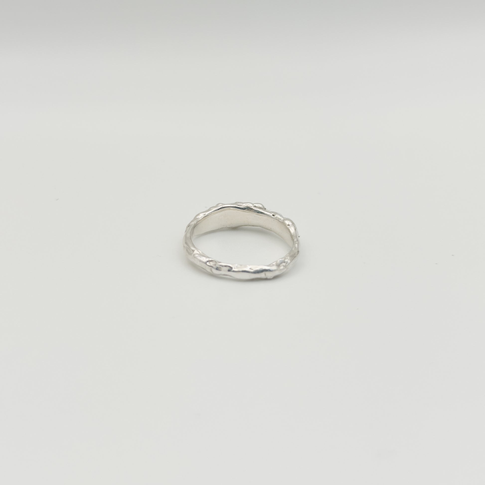 Back view of the Atoll textured silver ring, pictured on a light plain background.