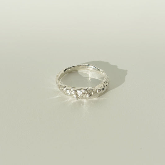 Front view of the Atoll textured silver ring, pictured on a light plain background.