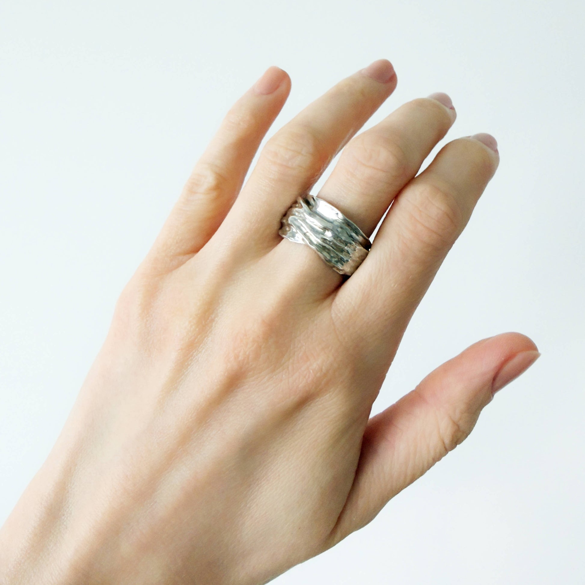 Hand wearing the Canyon sample silver ring on a plain background.