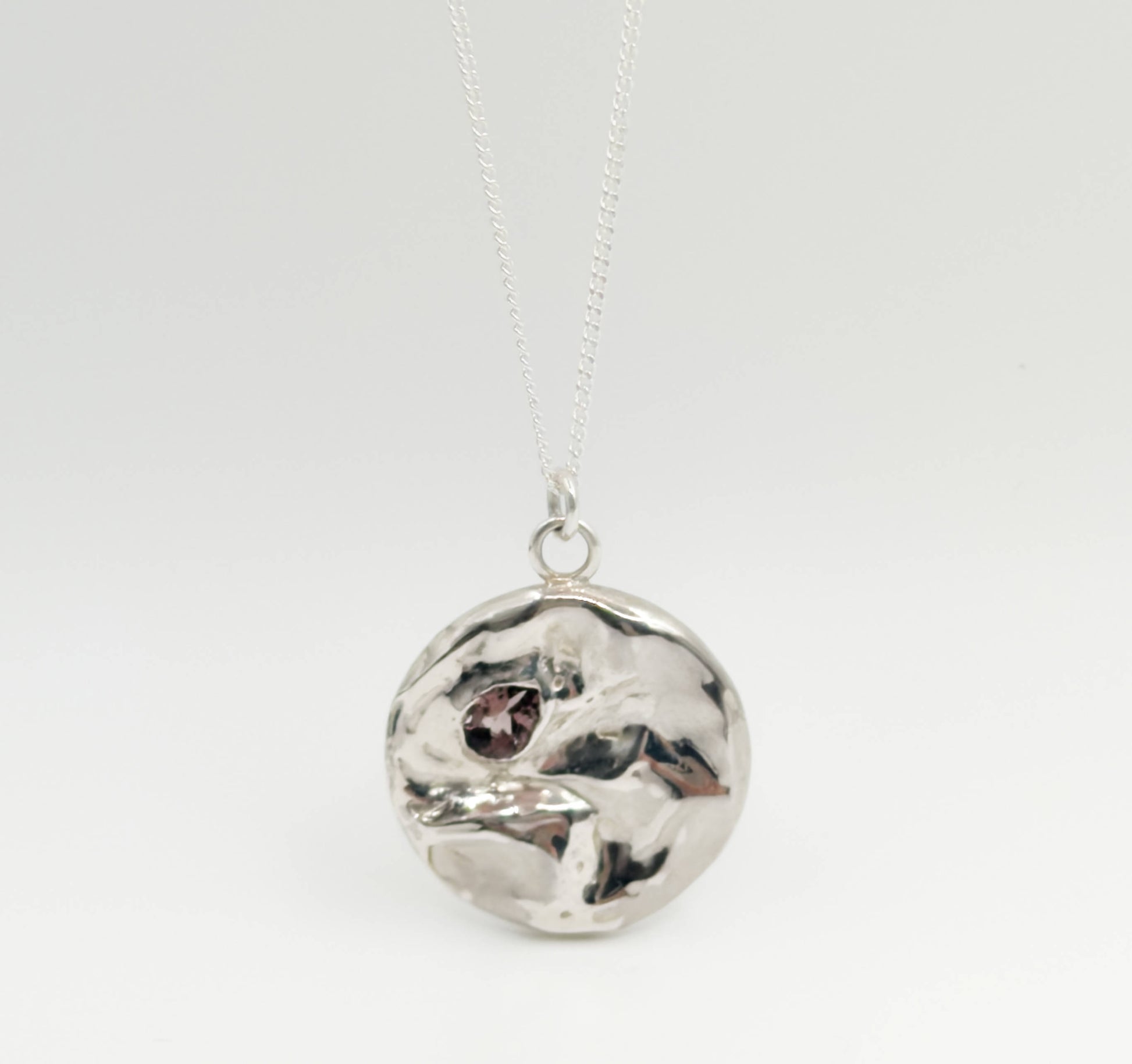 Front view of the Devotion silver necklace, featuring a round pendant. Pictured on a light plain background.