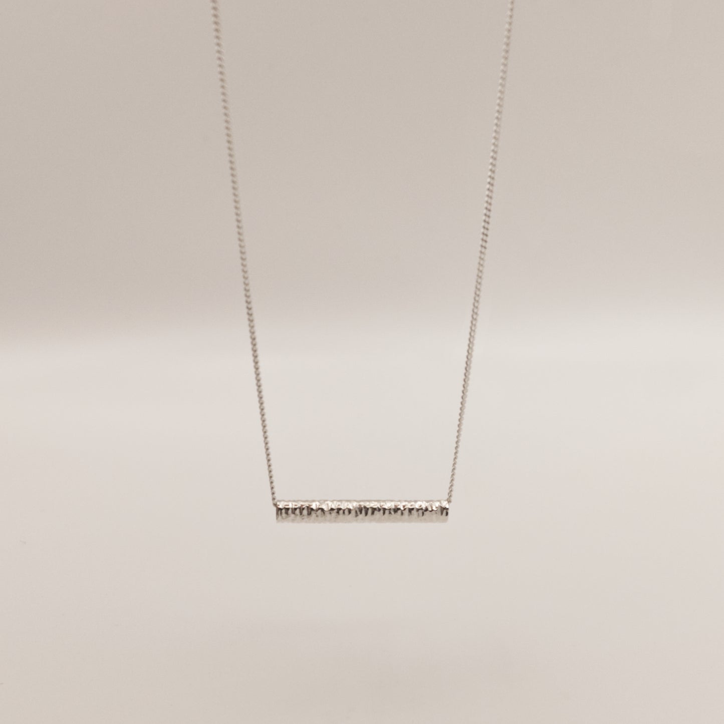Front view of the Echo textured silver pendant on a curb chain, pictured on a light plain background.