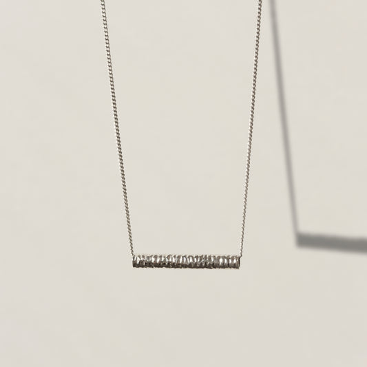 Front view of the Echo textured silver pendant on a curb chain, pictured on a light plain background.