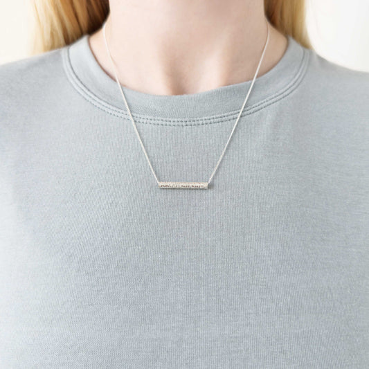 Echo textured silver pendant on a curb chain. Pictured on a person wearing a light blue-gray top.