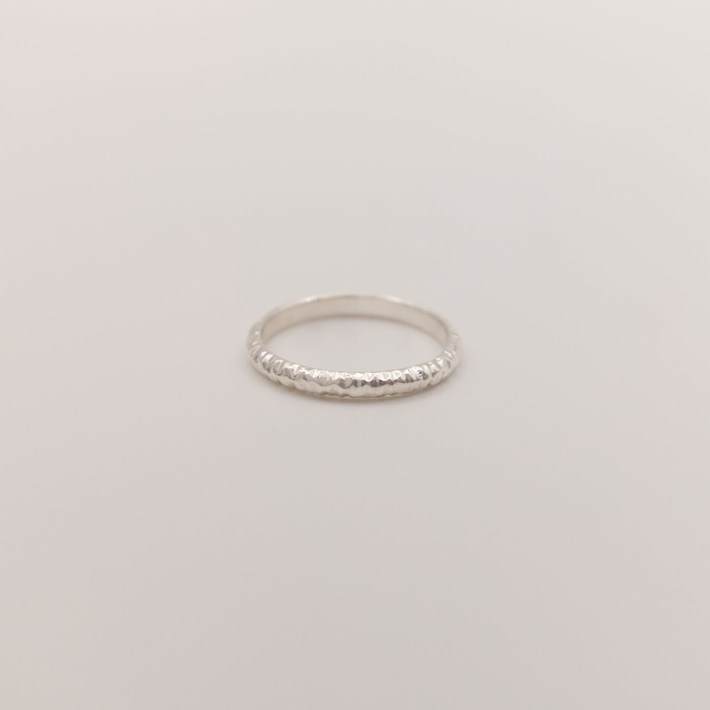 Front view of the Echo ring - a thin silver band ring with a textured surface, photographed on a plain light gray background.