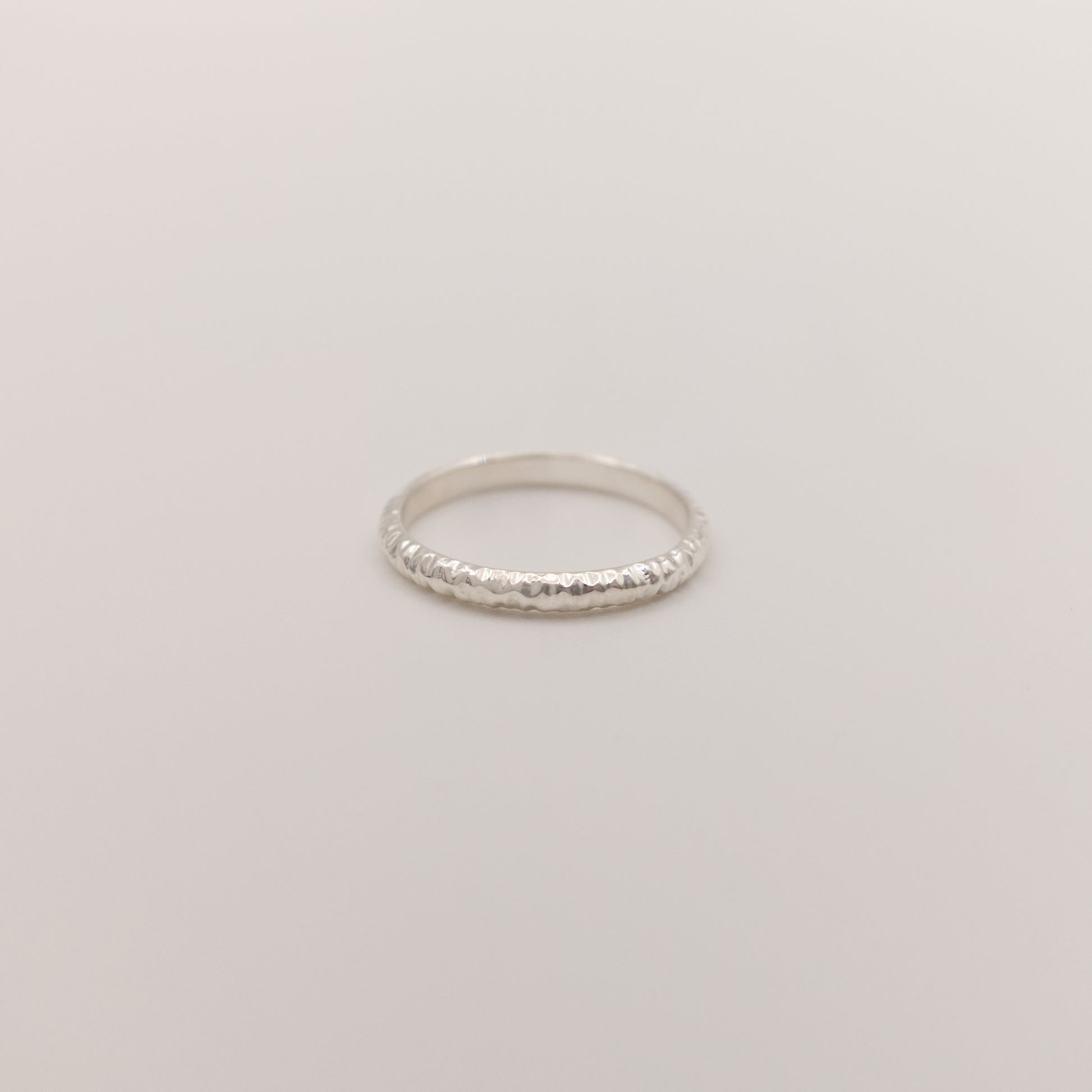 Front view of the Echo ring - a thin silver band ring with a textured surface, photographed on a plain light gray background.