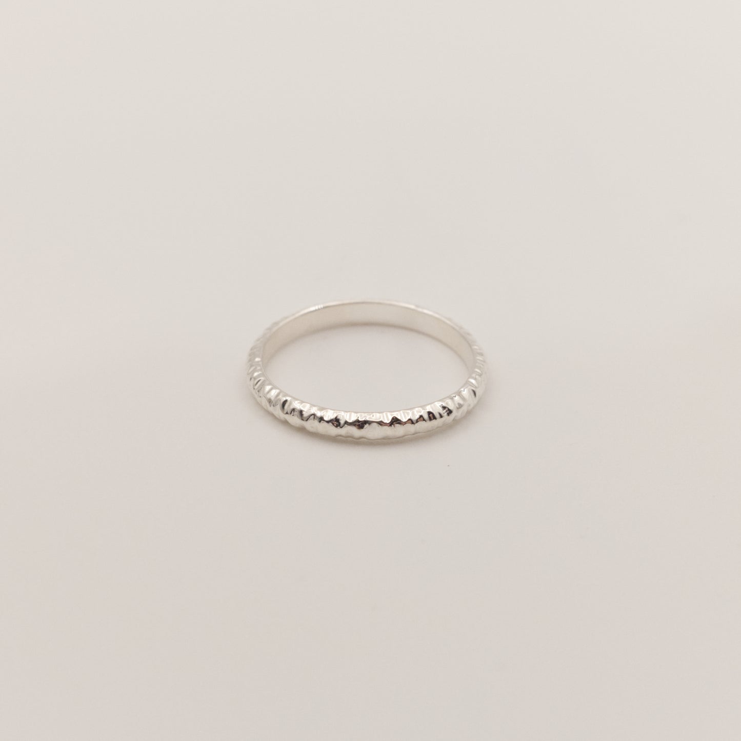 Front view of the Echo ring - a thin silver band ring with a textured surface, photographed on a plain light gray background.