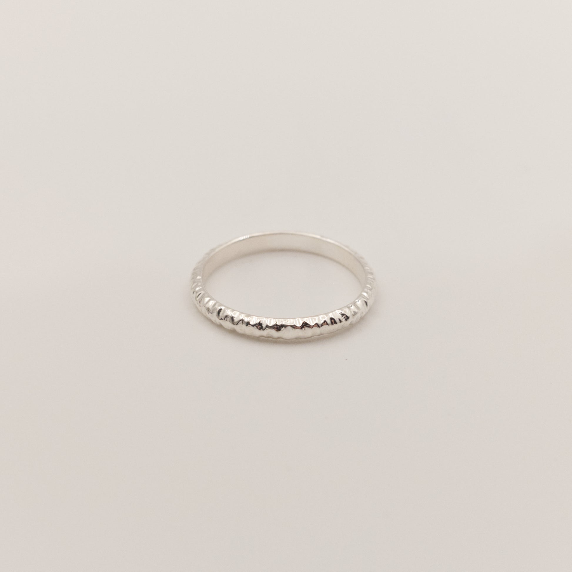 Front view of the Echo ring - a thin silver band ring with a textured surface, photographed on a plain light gray background.