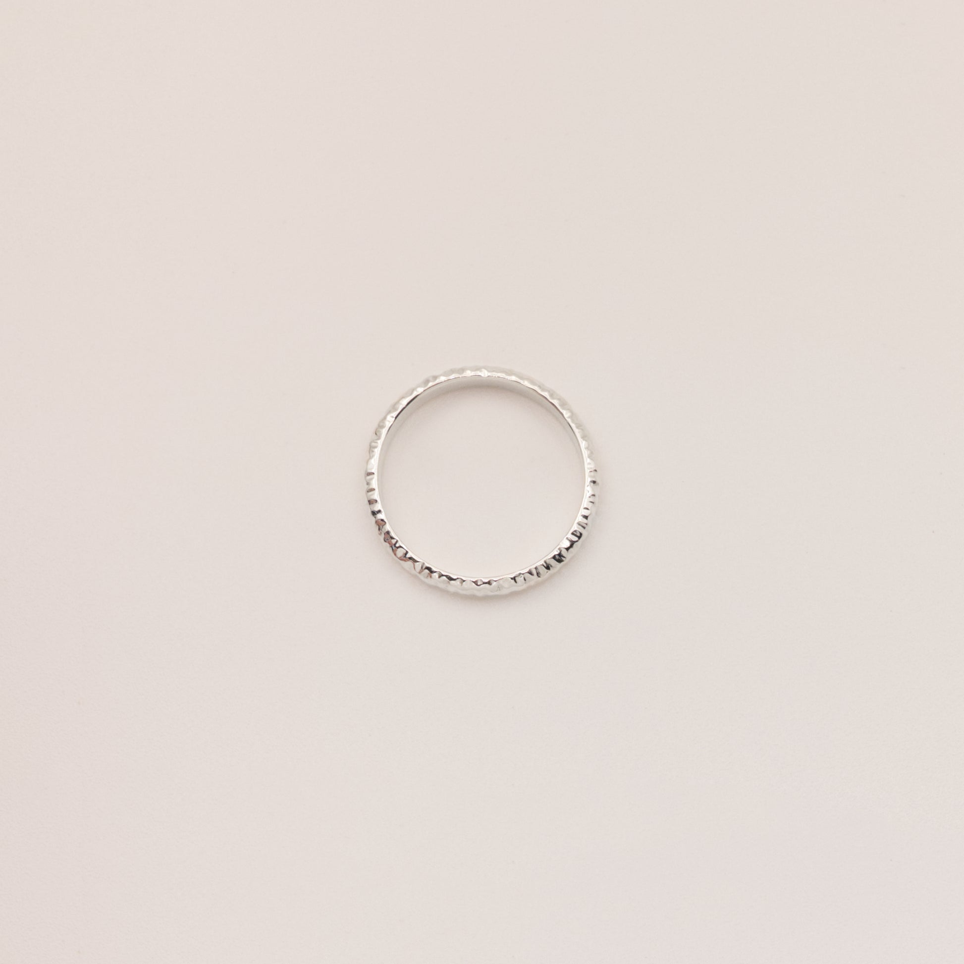 Top view of the Echo ring - a thin silver band ring with a textured surface, photographed on a plain light gray background.