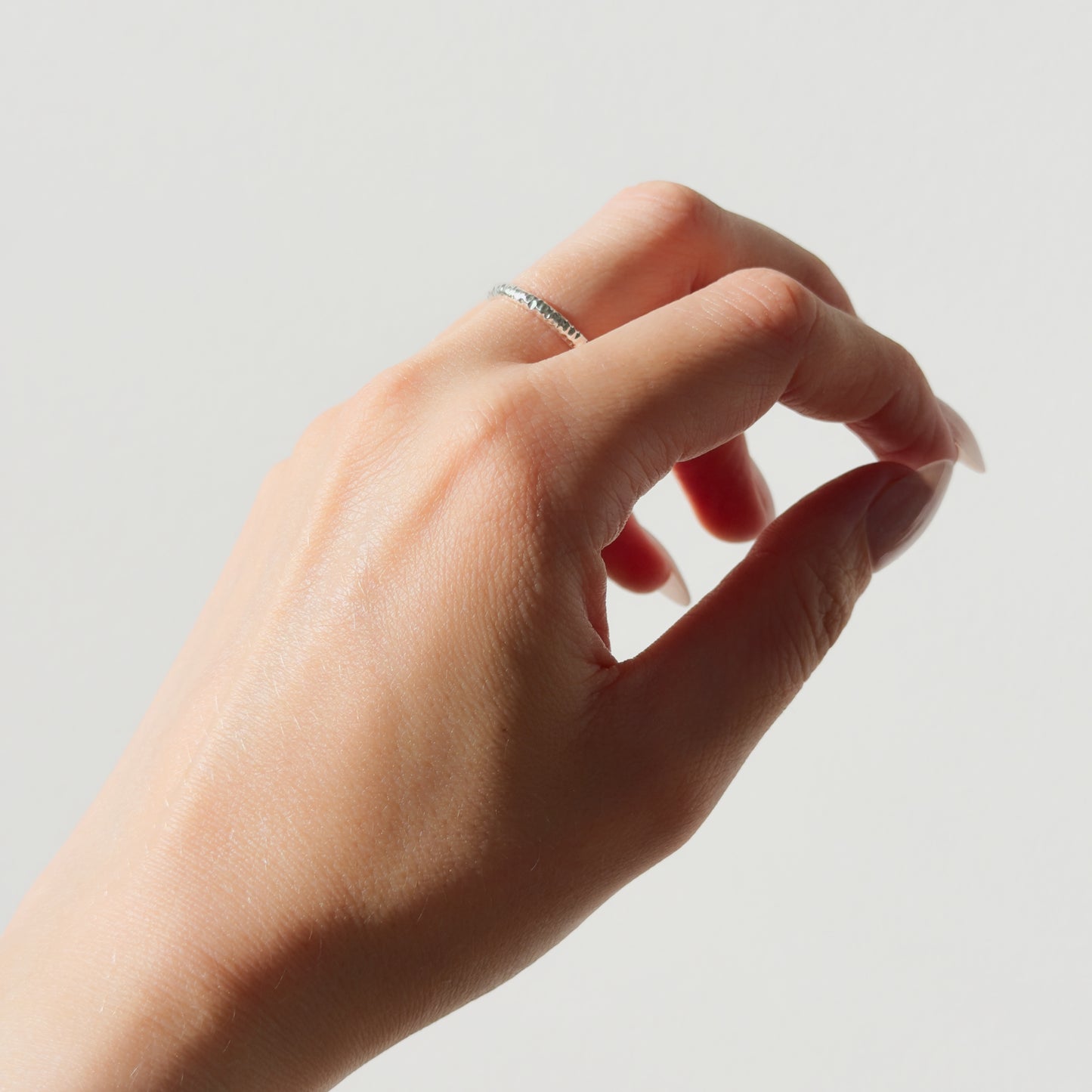 Hand wearing the Echo textured silver ring on a plain background.