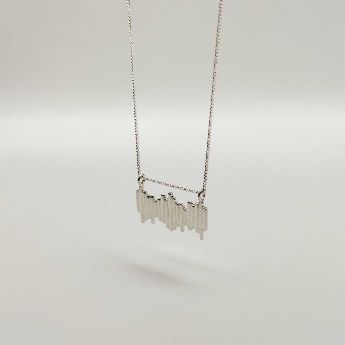 Angled front view of the Guidance textured silver necklace, pictured on a light plain background.