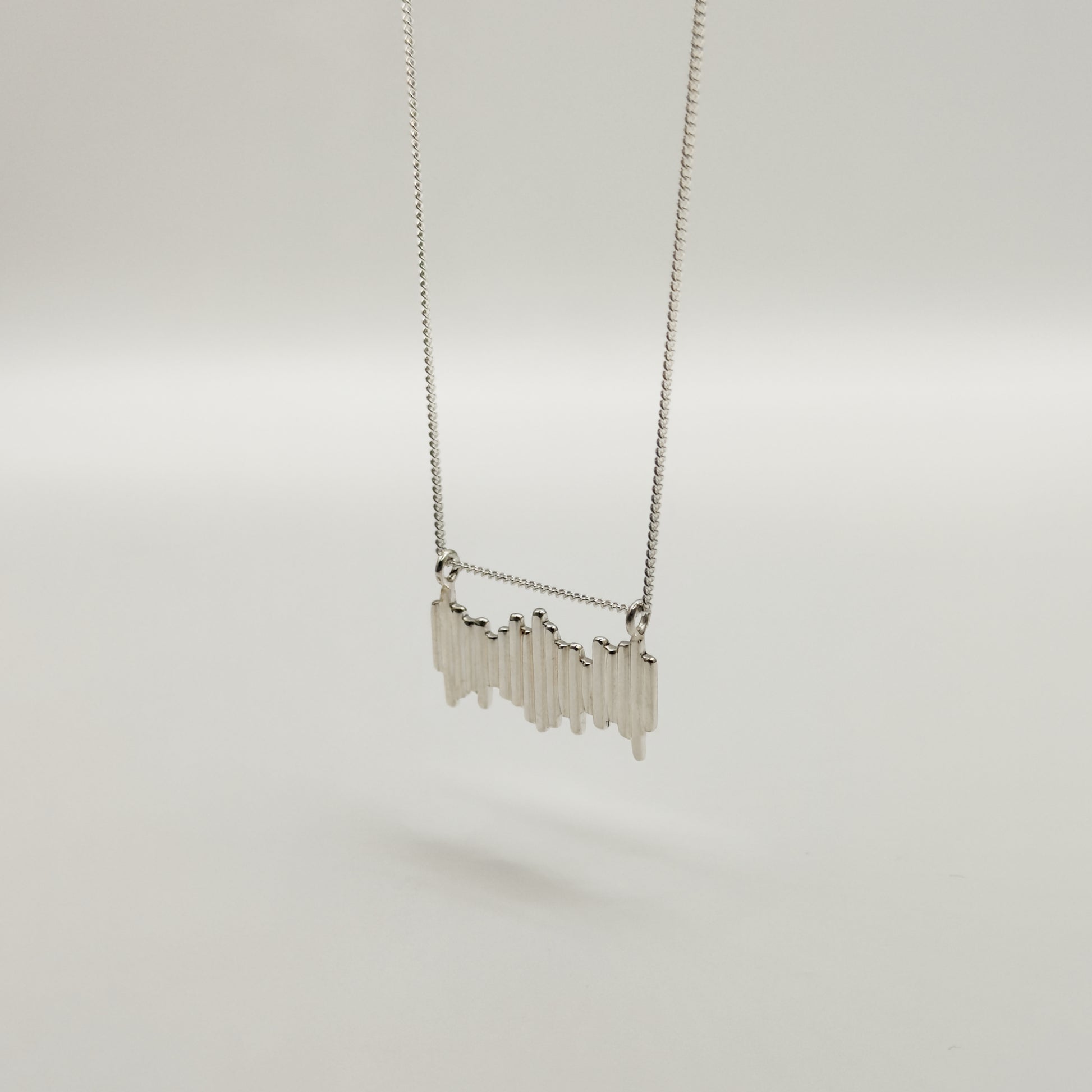 Angled front view of the Guidance textured silver necklace, pictured on a light plain background.