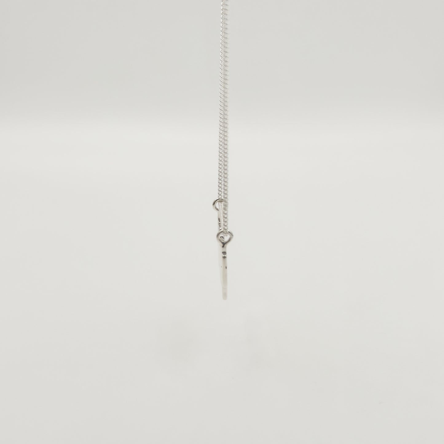 Side view of the Guidance textured silver necklace, pictured on a light plain background.