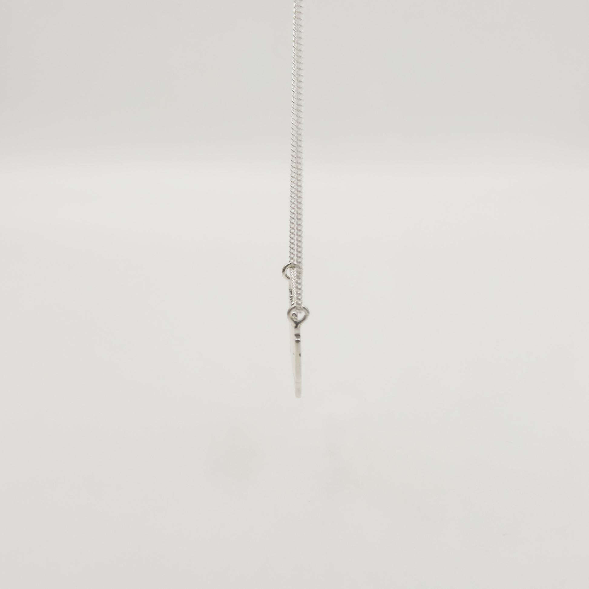 Side view of the Guidance textured silver necklace, pictured on a light plain background.