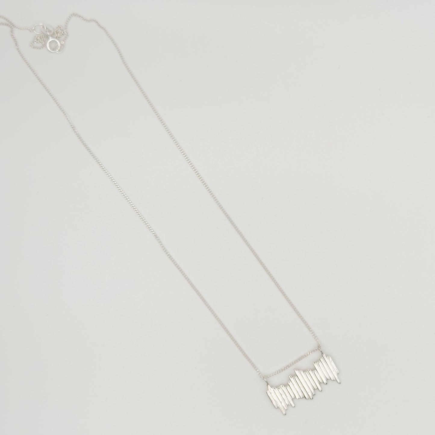 Top view of the Guidance textured silver necklace, pictured on a light plain background.