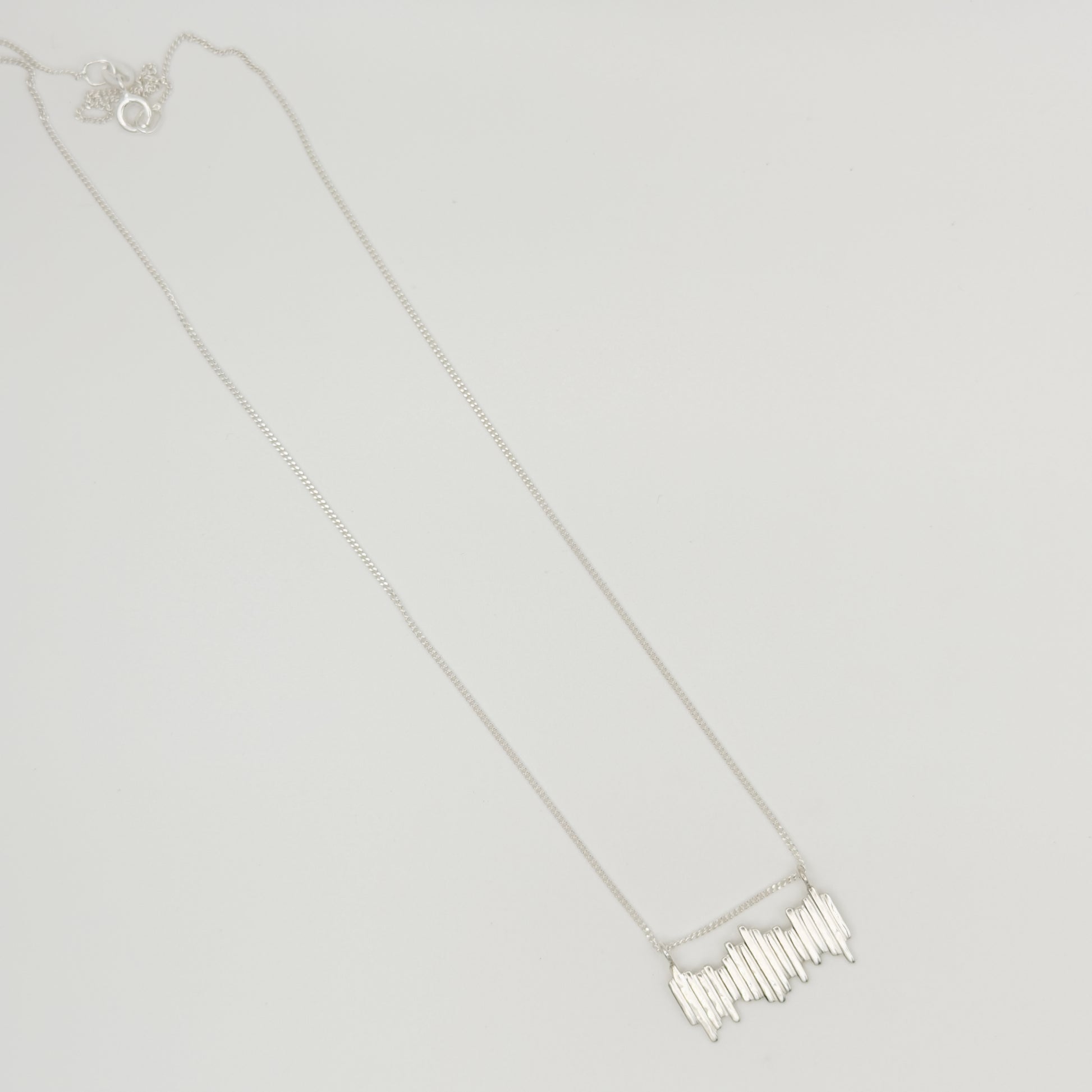 Top view of the Guidance textured silver necklace, pictured on a light plain background.
