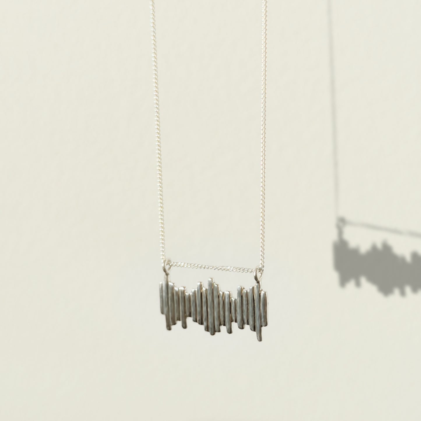 Angled front view of the Guidance textured silver necklace, pictured on a light plain background.