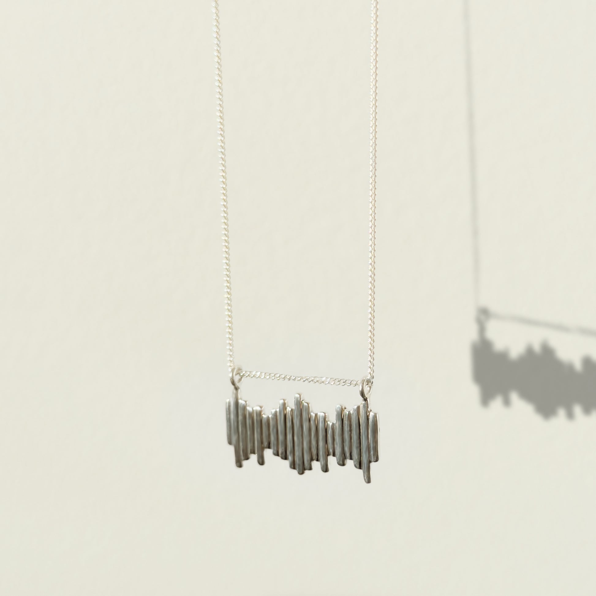 Angled front view of the Guidance textured silver necklace, pictured on a light plain background.