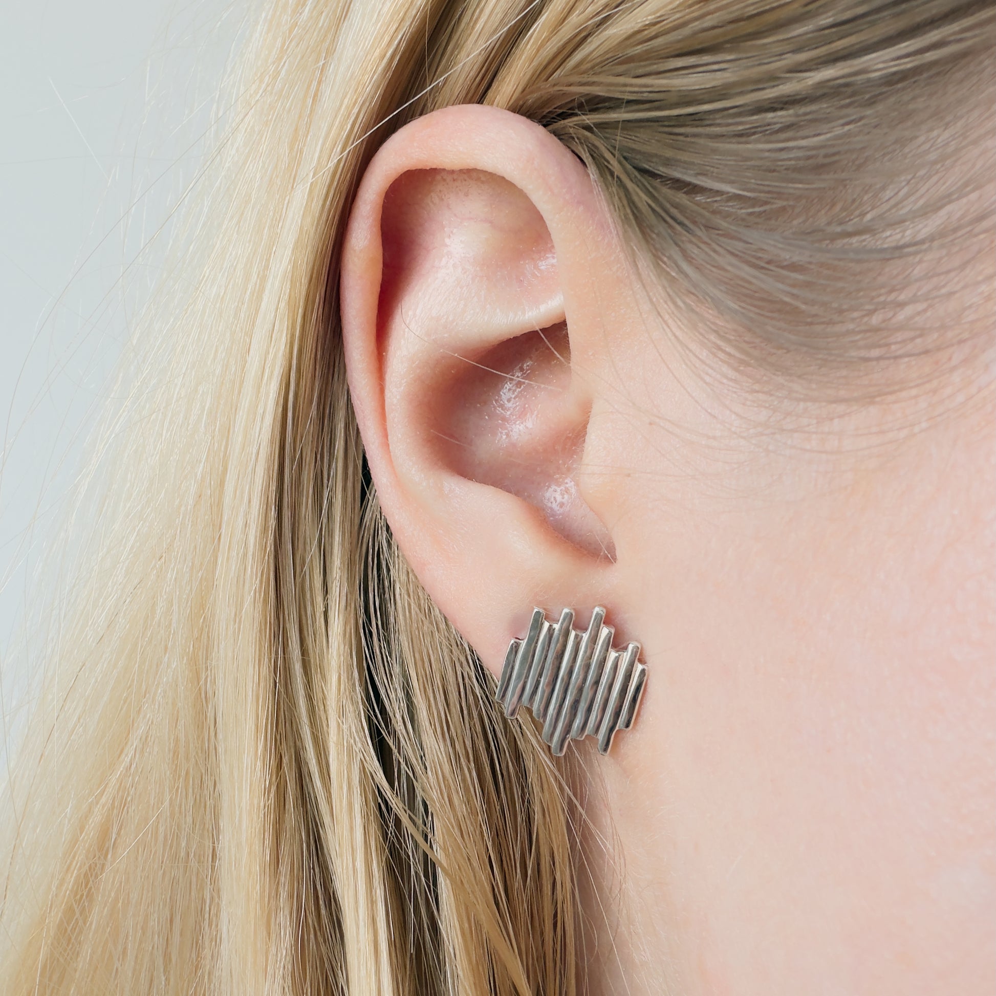 Close-up of an ear wearing the Guidance silver stud earring with blonde hair.