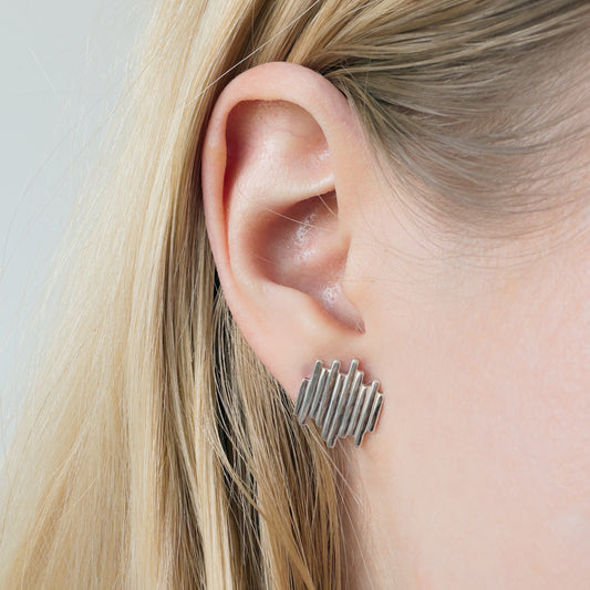 Close-up of an ear wearing the Guidance silver stud earring with blonde hair.