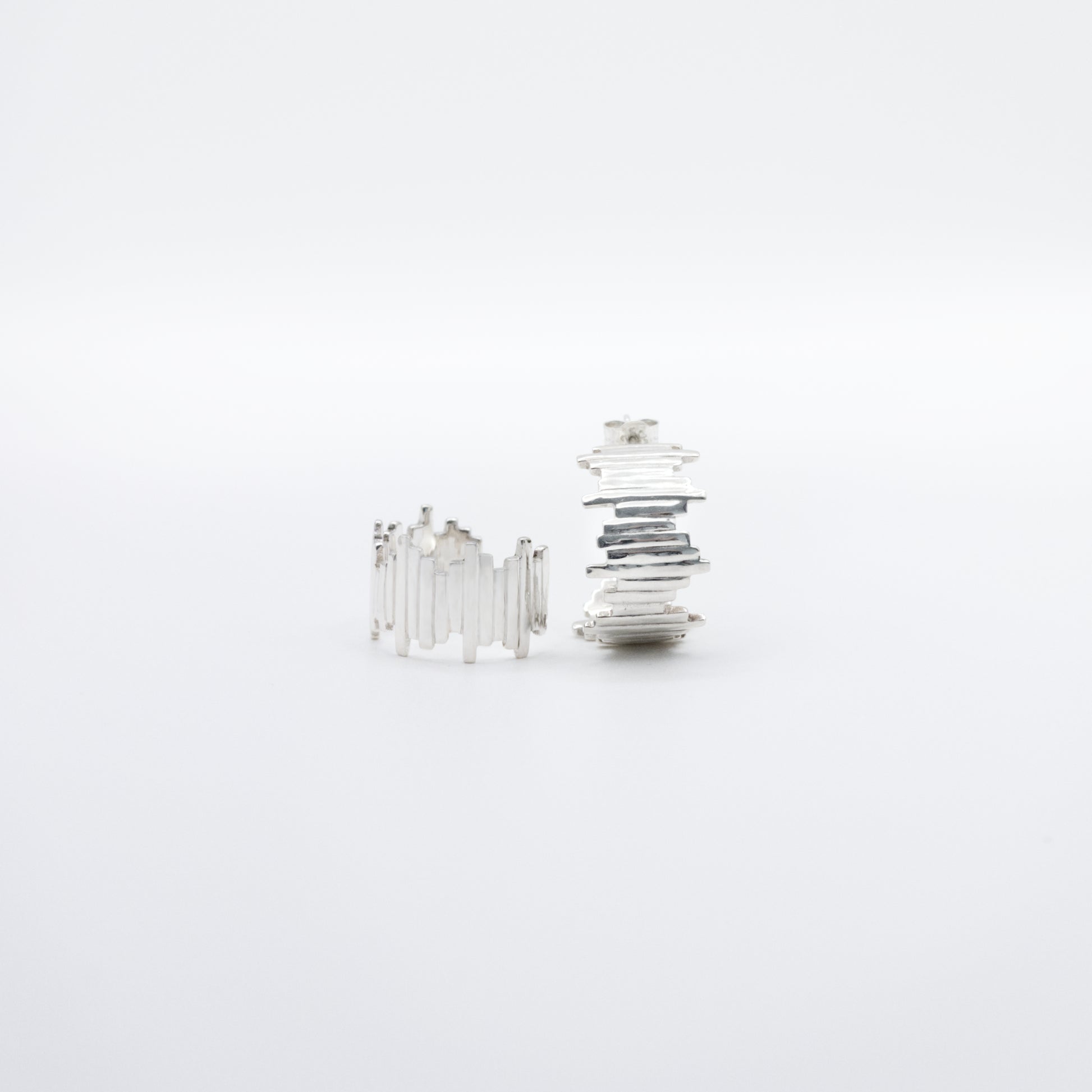 A pair of Guidance silver hoop earrings, front and side views, pictured on a light plain background.