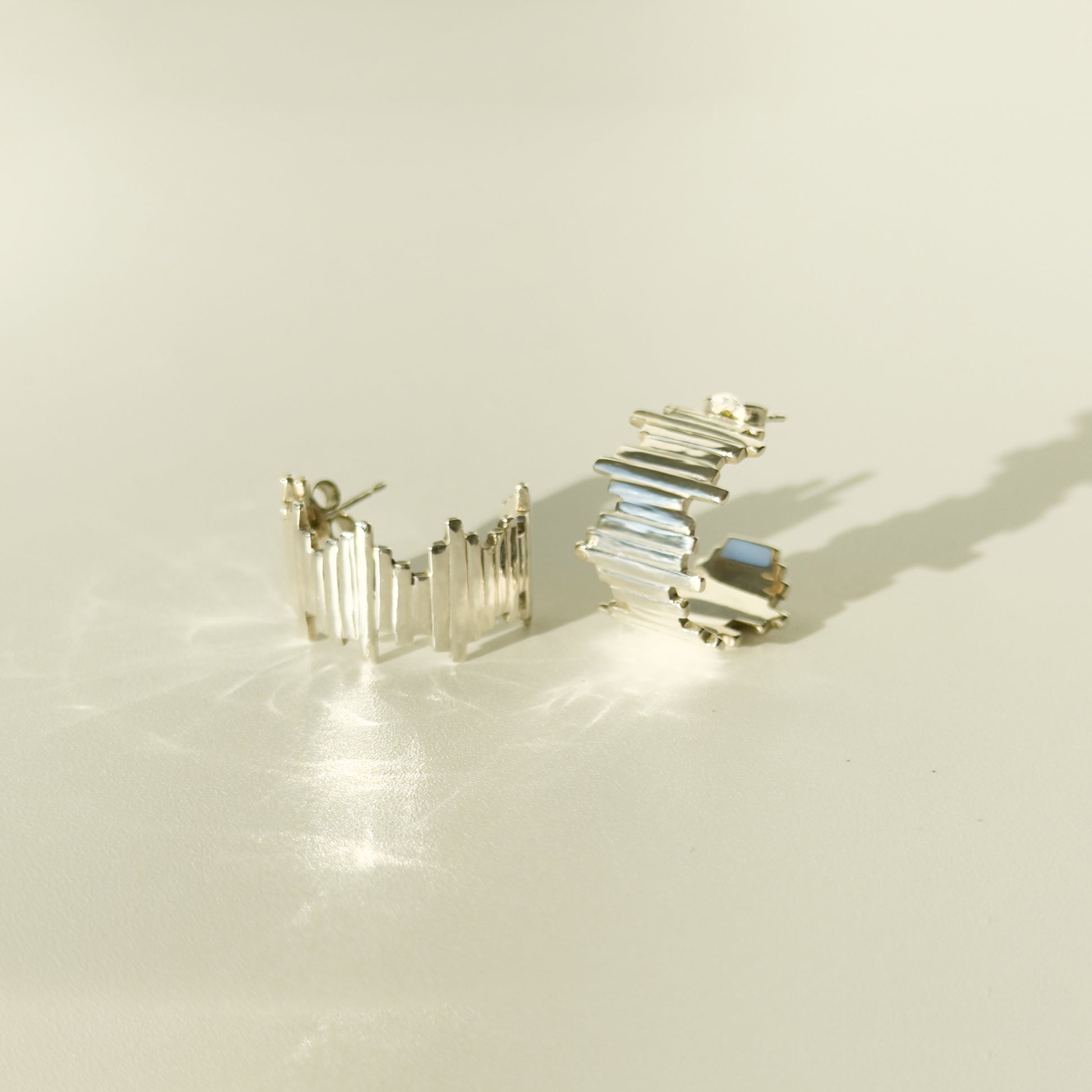 A pair of Guidance silver hoop earrings, front and side views, pictured on a light plain background.
