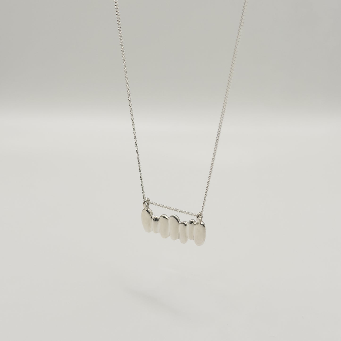 Angled front view of the Meridian textured silver necklace, pictured on a light plain background.