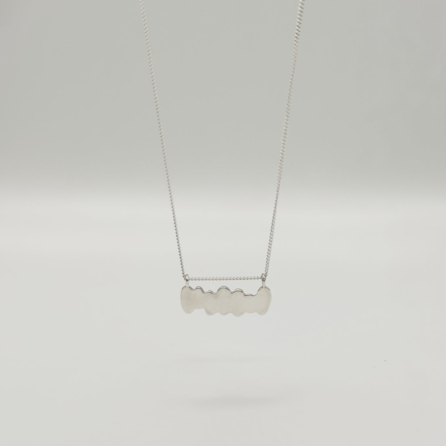 Back view of the Meridian textured silver necklace, pictured on a light plain background.