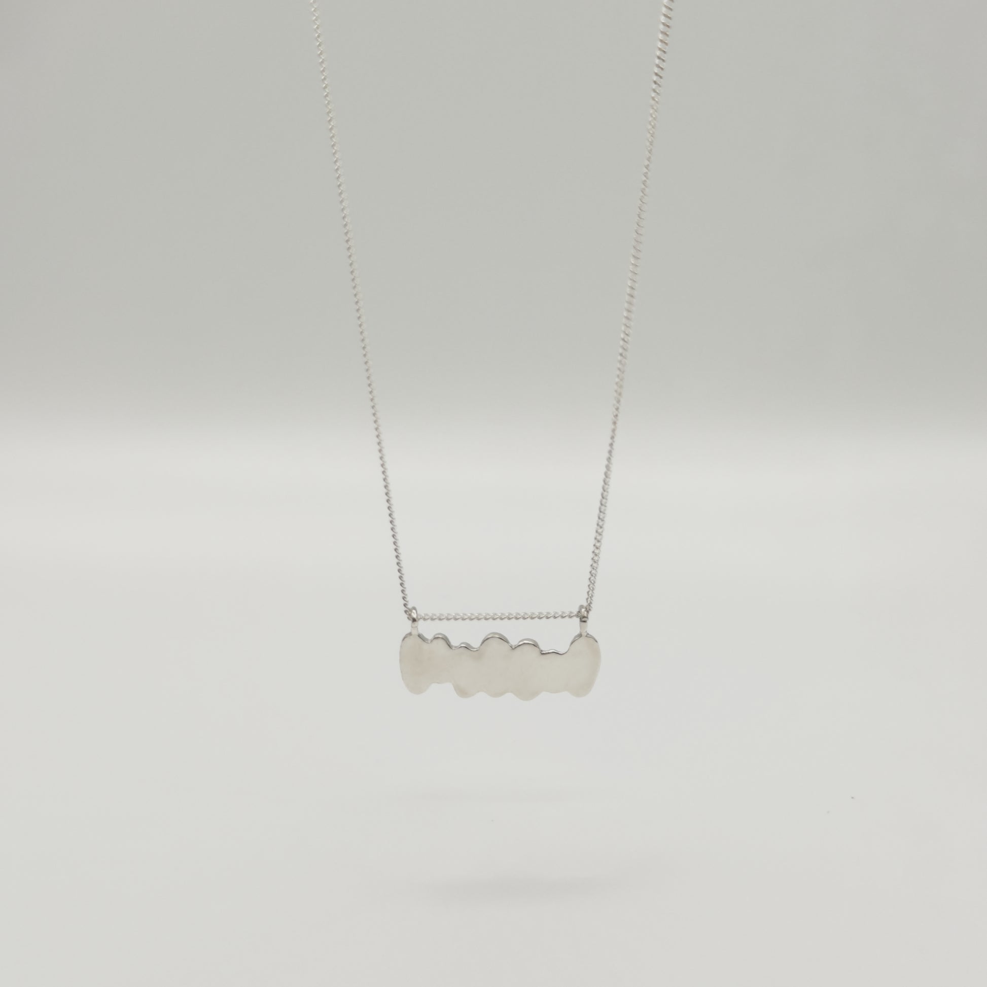 Back view of the Meridian textured silver necklace, pictured on a light plain background.